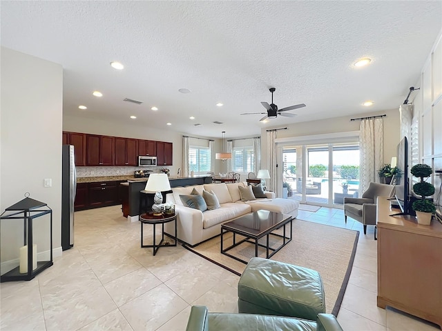 tiled living room featuring ceiling fan and a textured ceiling