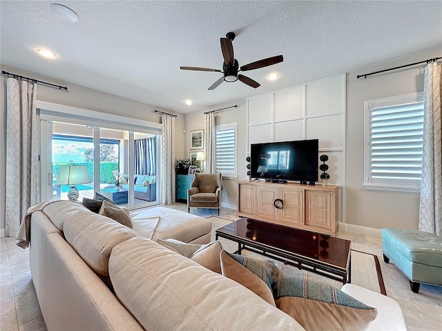 living room with light tile patterned flooring, ceiling fan, and a textured ceiling