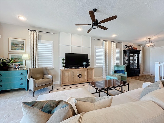 tiled living room featuring ceiling fan with notable chandelier, a wealth of natural light, and a textured ceiling