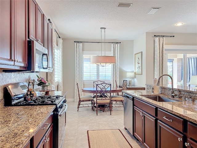 kitchen featuring sink, decorative light fixtures, light tile patterned floors, appliances with stainless steel finishes, and light stone countertops