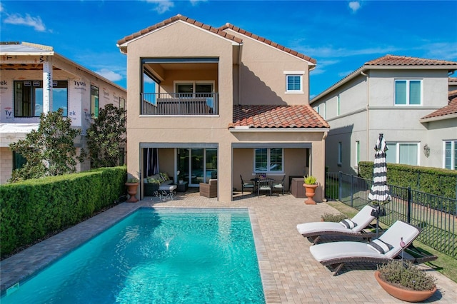 rear view of house featuring a balcony, an outdoor hangout area, a fenced in pool, and a patio area