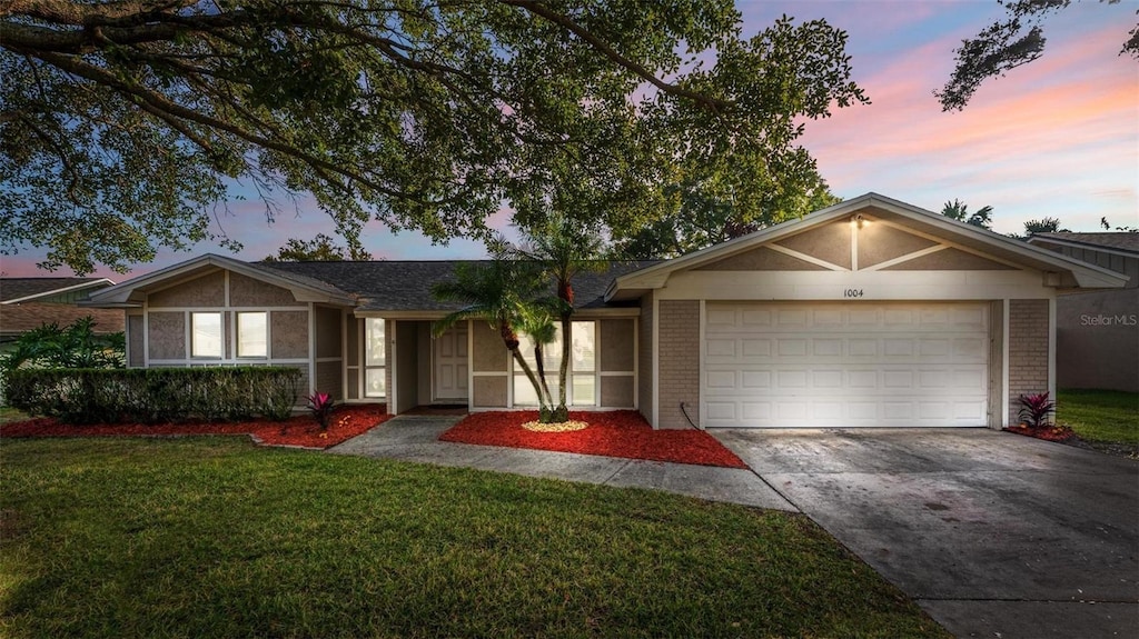 ranch-style house with a garage and a lawn