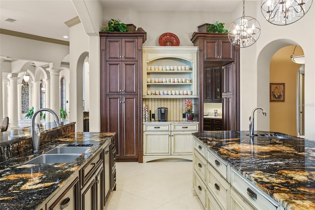 kitchen with arched walkways, visible vents, decorative light fixtures, and a sink