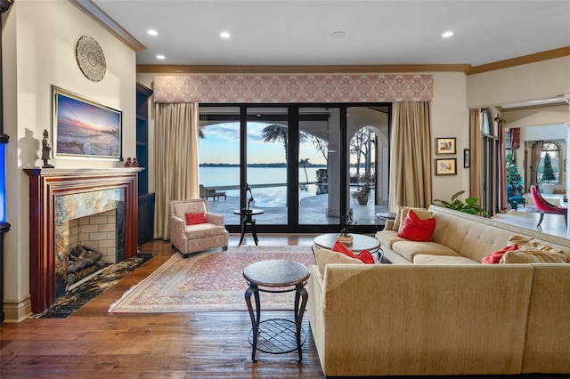 living area featuring plenty of natural light, a fireplace, crown molding, and wood finished floors