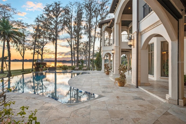 view of swimming pool with a patio, a pool with connected hot tub, and a water view