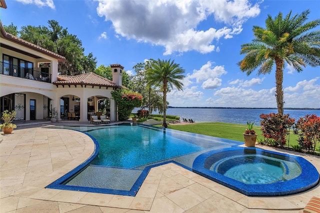 outdoor pool with a water view, a lawn, an in ground hot tub, and a patio area