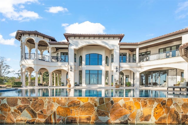 back of property featuring a patio, an outdoor pool, and stucco siding