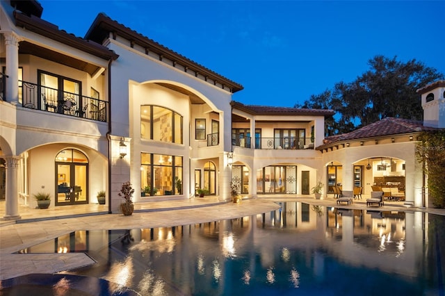 rear view of house featuring a patio, a tile roof, french doors, and stucco siding