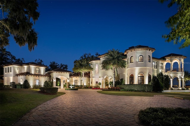 mediterranean / spanish-style house with stucco siding, curved driveway, and a lawn