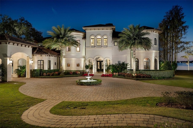 mediterranean / spanish-style home featuring stucco siding, curved driveway, and french doors