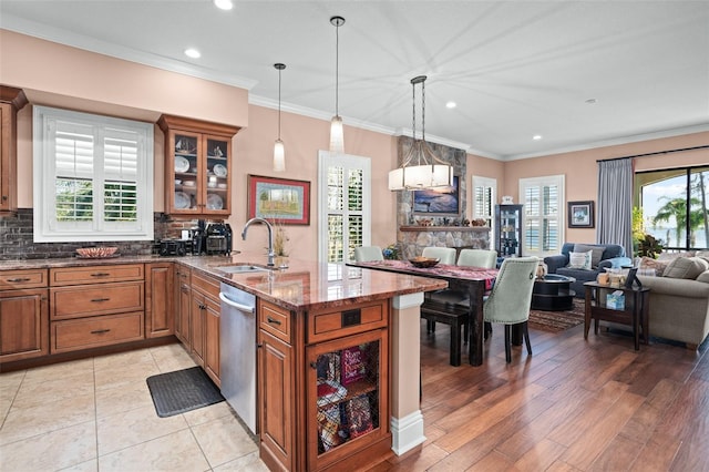 kitchen with a sink, tasteful backsplash, brown cabinetry, glass insert cabinets, and dishwasher