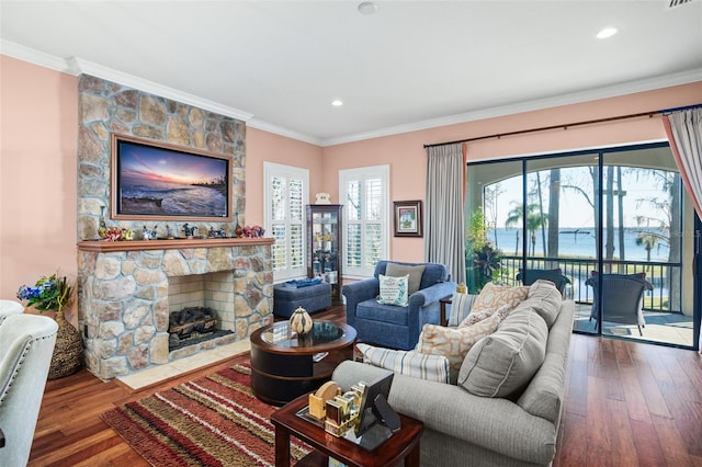 living room with a stone fireplace, wood finished floors, and crown molding