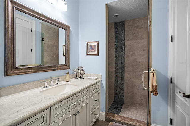 bathroom featuring vanity, a shower stall, and a textured ceiling