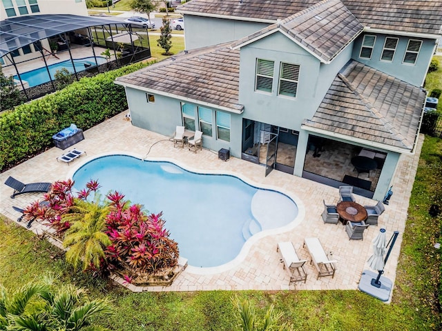 view of swimming pool featuring a fire pit, a patio area, and glass enclosure