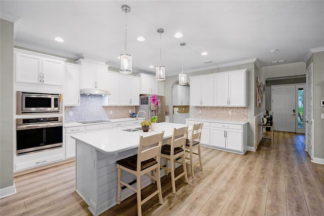 kitchen featuring pendant lighting, white cabinetry, a center island with sink, and appliances with stainless steel finishes