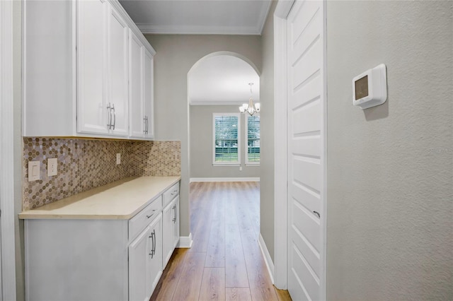 interior space featuring white cabinetry, crown molding, tasteful backsplash, and light wood-type flooring