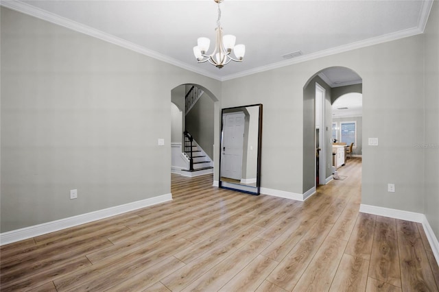 spare room with an inviting chandelier, ornamental molding, and light hardwood / wood-style floors