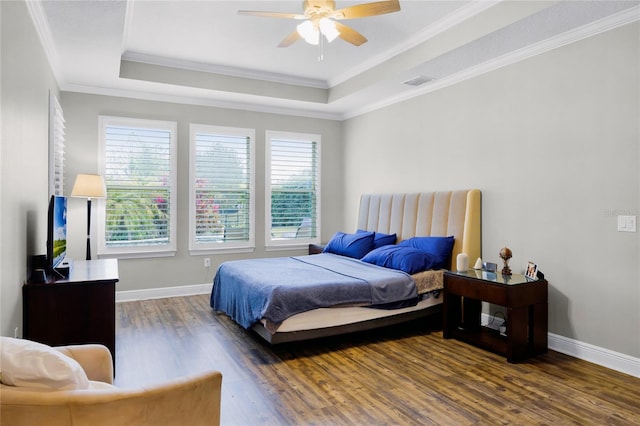 bedroom with dark wood-type flooring, ceiling fan, ornamental molding, and a raised ceiling