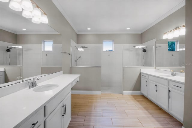 bathroom with vanity, plenty of natural light, ornamental molding, and a tile shower