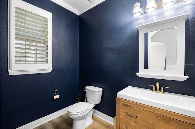 bathroom with wood-type flooring, vanity, crown molding, and toilet