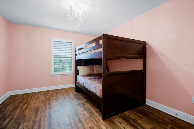 unfurnished bedroom with an inviting chandelier, a textured ceiling, and dark hardwood / wood-style flooring