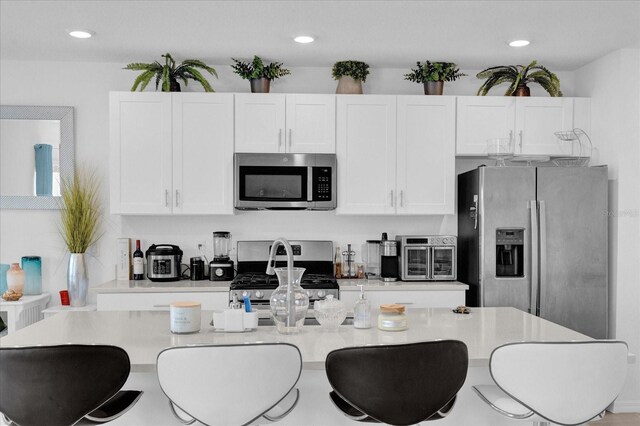 kitchen with white cabinetry, a kitchen bar, and appliances with stainless steel finishes