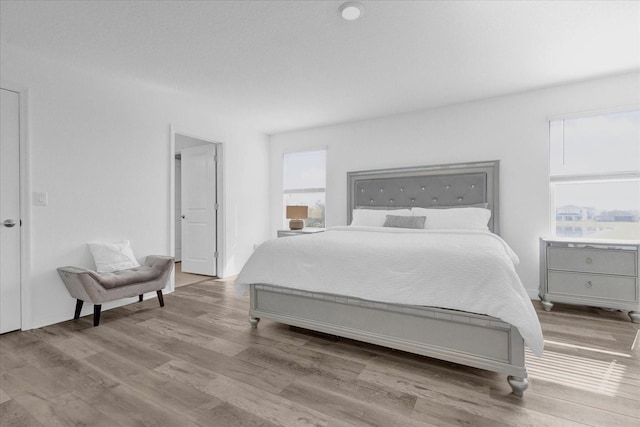 bedroom with light hardwood / wood-style floors and multiple windows