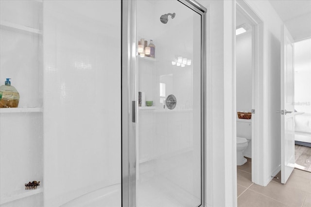 bathroom with tile patterned flooring, an enclosed shower, and toilet