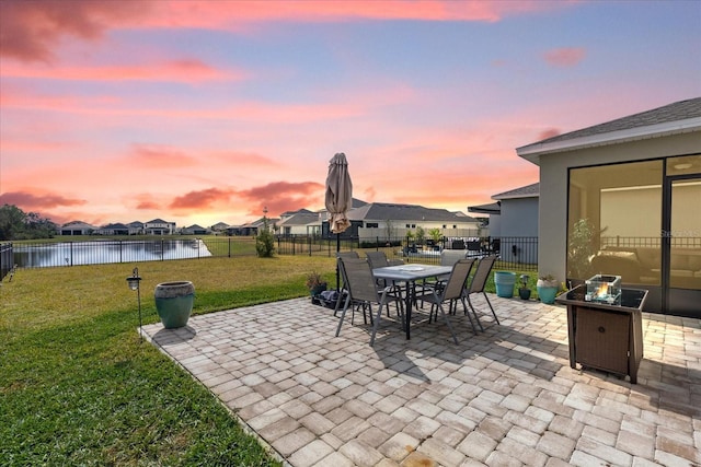 patio terrace at dusk with a water view and a lawn