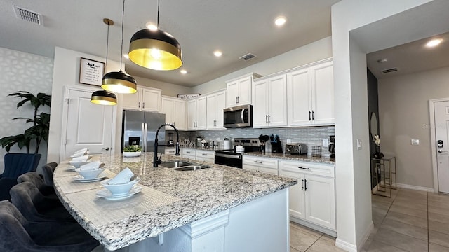 kitchen with a kitchen island with sink, sink, white cabinets, and appliances with stainless steel finishes