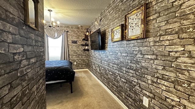 hall with brick wall, carpet flooring, a textured ceiling, and a notable chandelier