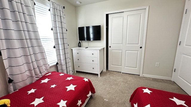 bedroom with multiple windows, light carpet, and a closet