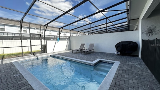 view of pool with grilling area, a patio, and glass enclosure