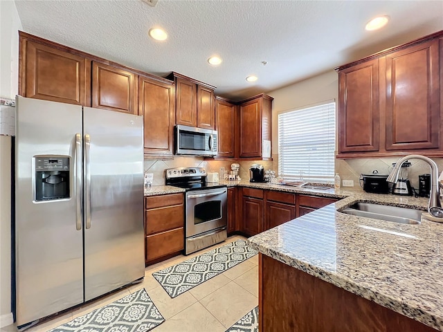 kitchen featuring sink, light tile patterned flooring, stainless steel appliances, and light stone countertops