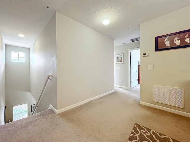 empty room with light carpet and a textured ceiling