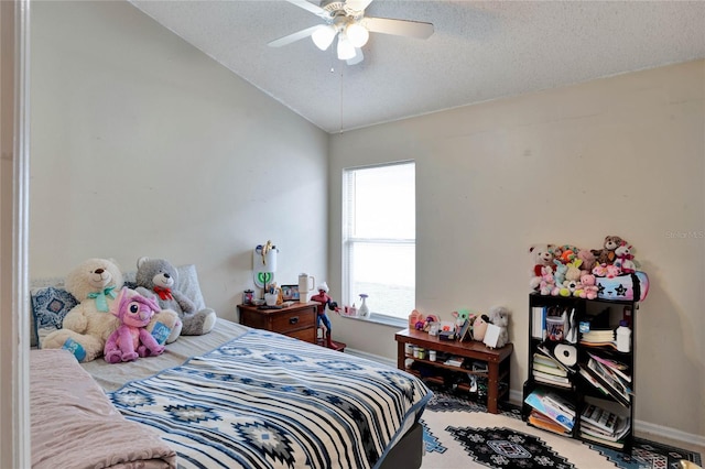 bedroom with lofted ceiling, a textured ceiling, a ceiling fan, and baseboards