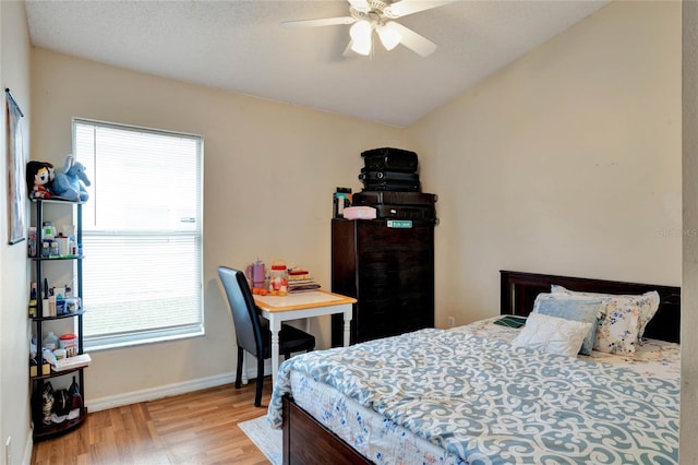 bedroom with a ceiling fan, light wood-type flooring, vaulted ceiling, and baseboards