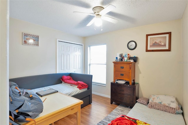 bedroom featuring light wood-style floors, ceiling fan, a textured ceiling, and a closet