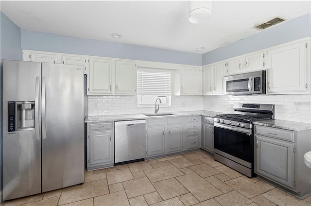 kitchen featuring tasteful backsplash, appliances with stainless steel finishes, gray cabinets, and sink