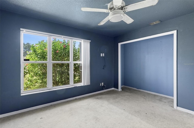 unfurnished bedroom featuring a textured ceiling, carpet floors, a closet, and ceiling fan