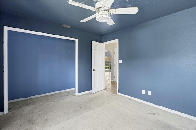 unfurnished bedroom featuring ceiling fan, light colored carpet, and a closet