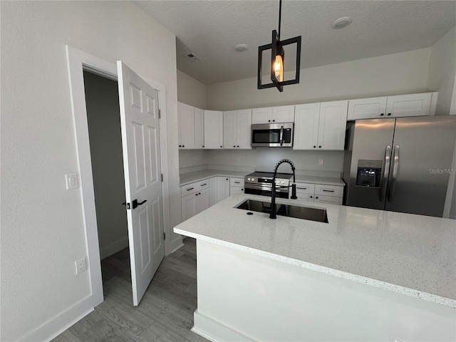 kitchen featuring hanging light fixtures, appliances with stainless steel finishes, sink, and white cabinets