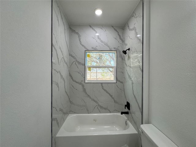 bathroom featuring toilet and tiled shower / bath combo