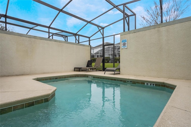 view of pool with glass enclosure and a patio area