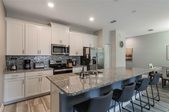 kitchen featuring white cabinetry, an island with sink, and appliances with stainless steel finishes