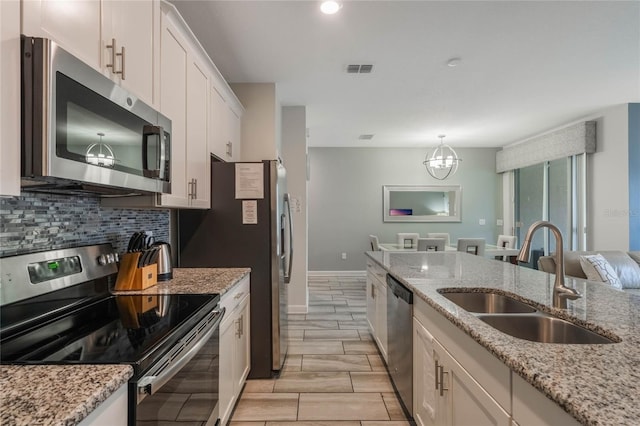 kitchen with white cabinetry, sink, stainless steel appliances, and light stone countertops