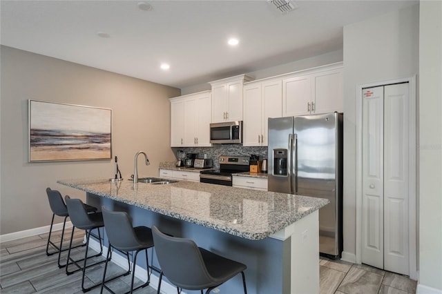 kitchen featuring white cabinetry, stainless steel appliances, a kitchen island with sink, and sink