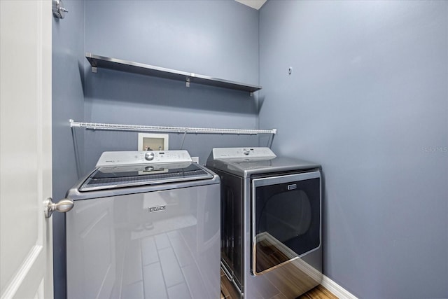 clothes washing area with wood-type flooring and washer and clothes dryer