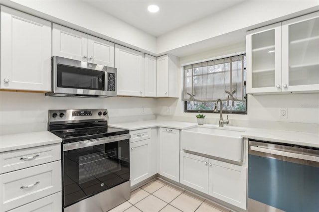 kitchen with sink, light tile patterned floors, white cabinets, and appliances with stainless steel finishes