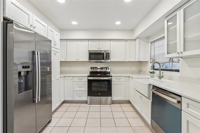 kitchen with white cabinetry, appliances with stainless steel finishes, light tile patterned flooring, and sink